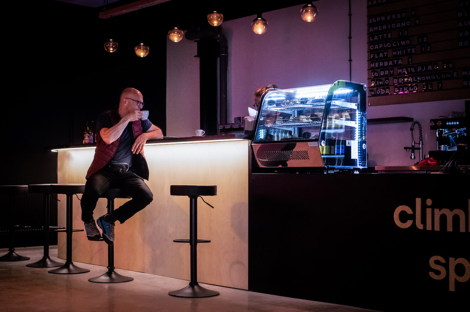 Zdjęcie pokazujące mężczyznę pijącego kawę w kawiarni Flow Climbing Space.